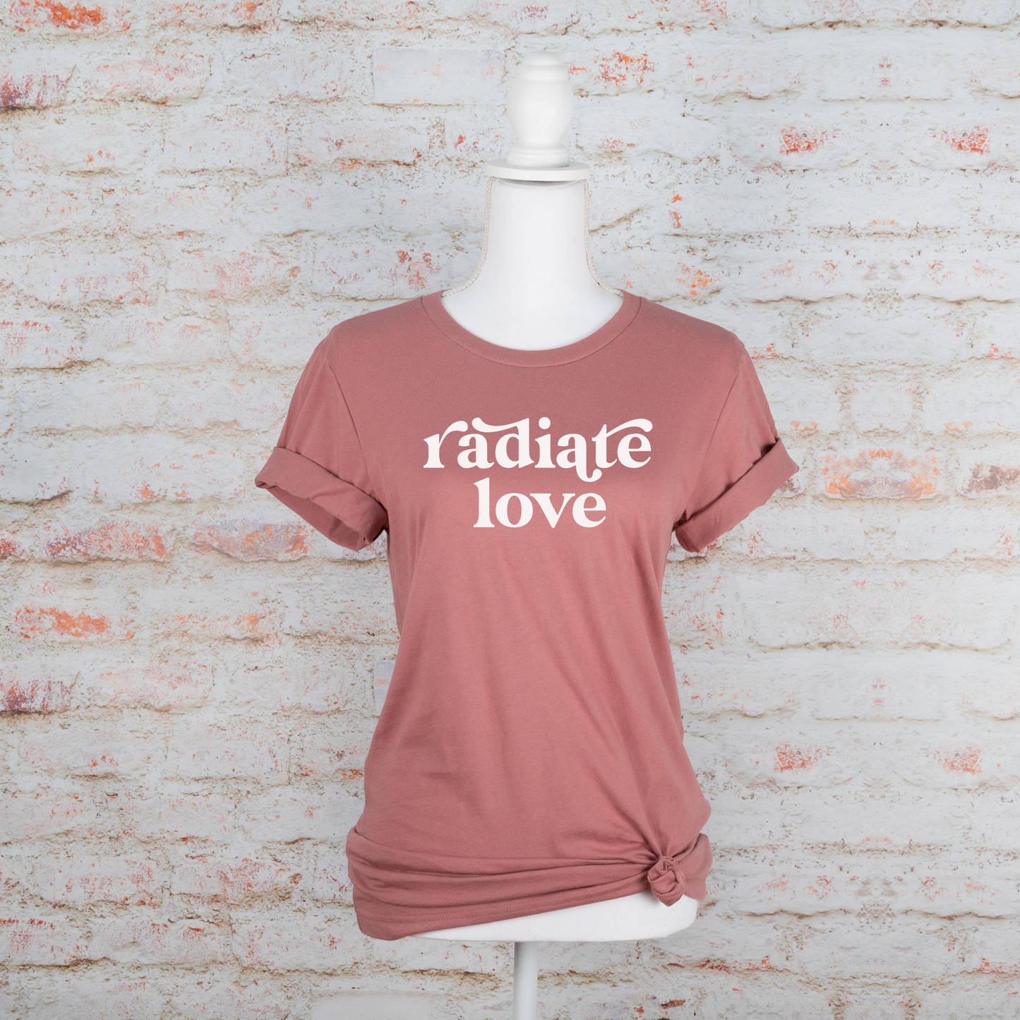 Mauve t-shirt with white text "radiate love" on front, upper center. Tee pictured on mannequin.